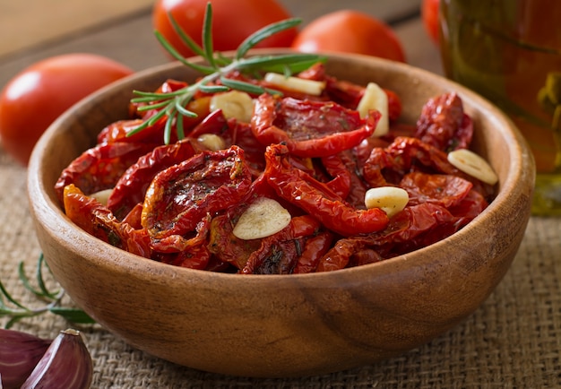 In de zon gedroogde tomaten met kruiden en knoflook in houten kom