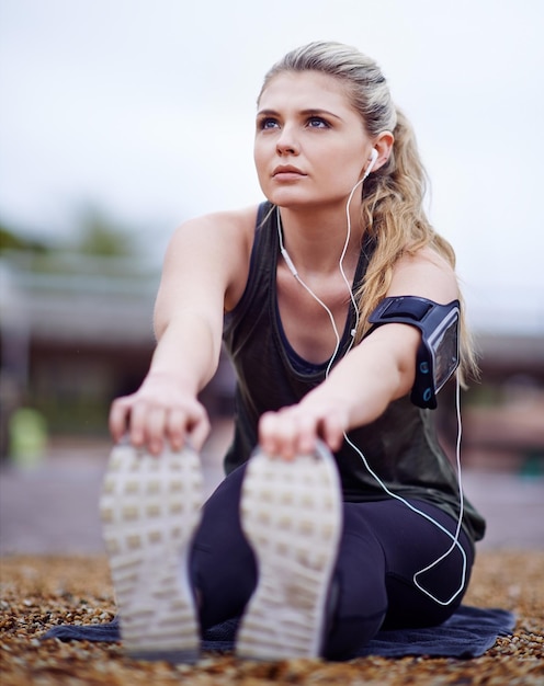 In de zone komen met geweldige muziek Shot van een jonge vrouw die haar benen strekt voor een run