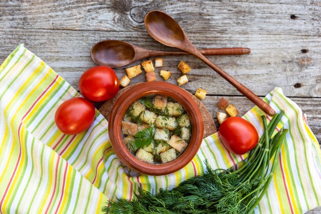 In een aarden pot, hete soep met croutons op een houten tafel.