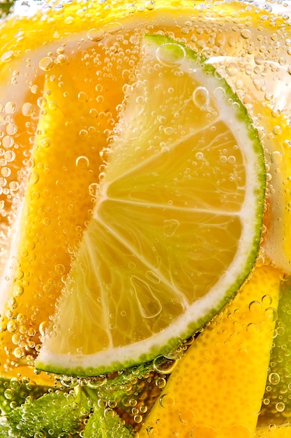 In een helder glas muntblad schijfjes limoen en citroen met bubbels macro foto van zomerdrank mojito