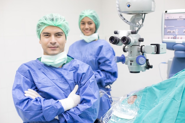 In een moderne operatiekamer Arts en team op zoek naar de camera met een glimlach.