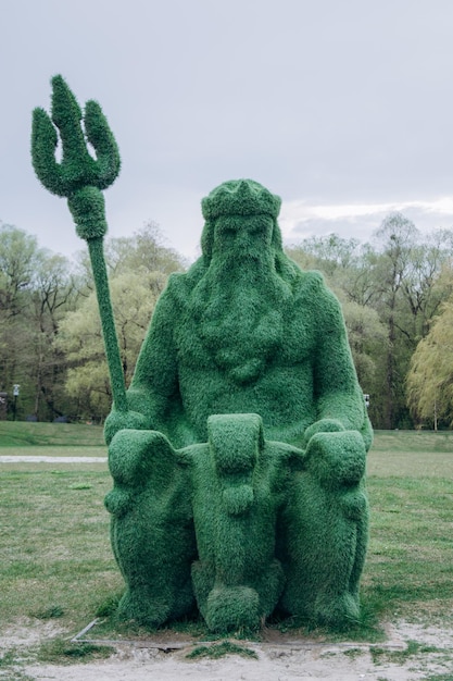 In een park staat een standbeeld van een man met een drietand op zijn hoofd.