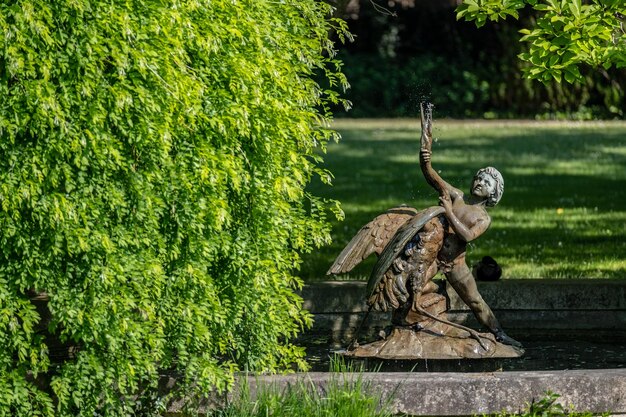 In een tuin staat een beeld van een vrouw met vleugels