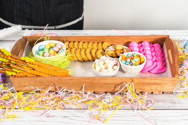 In elkaar zetten van een charcuteriebord met paassnoepjes, koekjes en marshmallows.