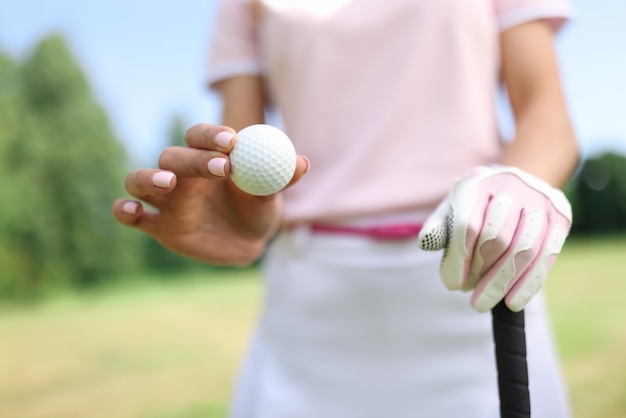 In hand van golfbal houdt de tweede gehandschoende hand golfclub.