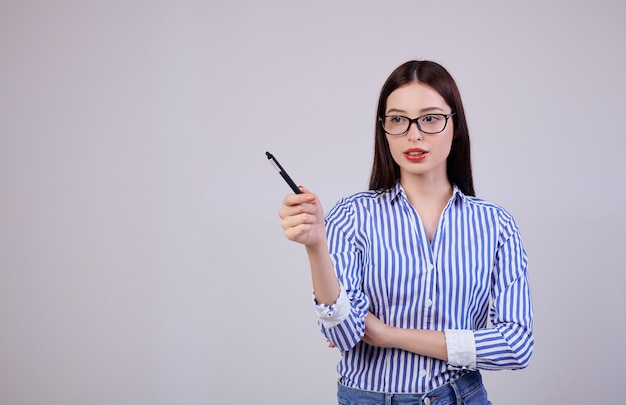 In het is een aangename flirterige jonge zakenvrouw met bruin haar en een bril. vrouw houdt een zwarte pen in haar hand.