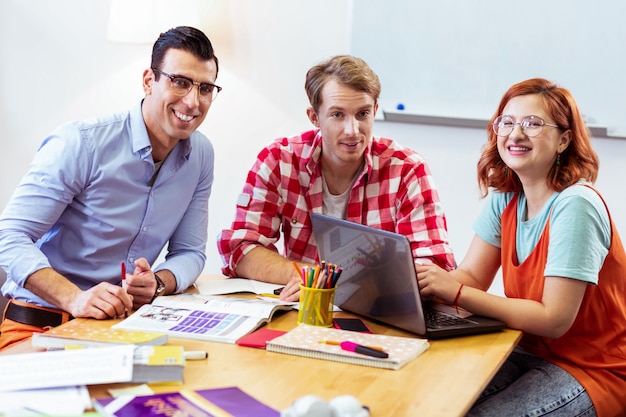 In het klaslokaal. Vrolijke positieve mensen die aan tafel zitten terwijl ze in de klas zijn