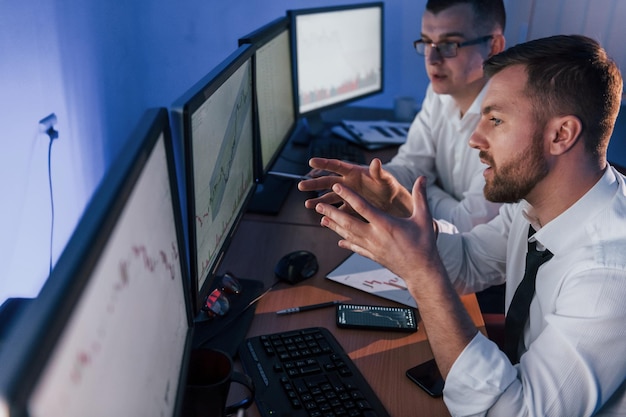 Foto in officiële kleding twee beurshandelaren aan het werk op kantoor met uitwisselingstechnologie