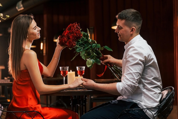 In rode jurk en wit overhemd Romantisch paar dineren in het restaurant