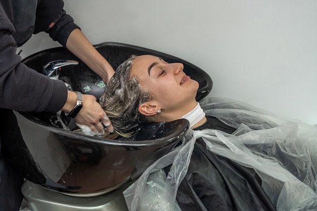 In schoonheidssalons wassen gekwalificeerde meesters hun hoofd voor haarbehandelingen Haarwasconcept Het concept van schoonheidssalons en hun service