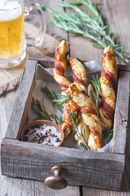 Foto in spek gewikkelde breadsticks met mok bier