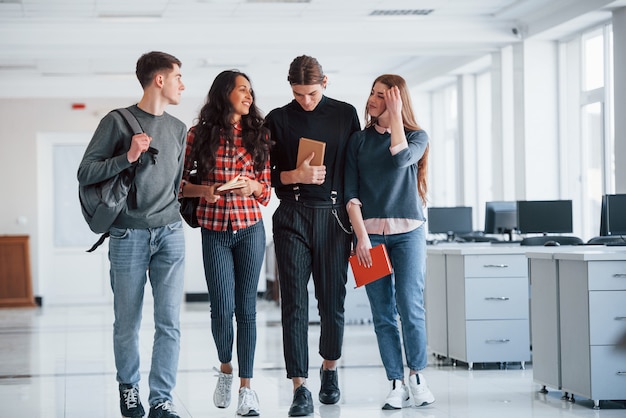 In verschillende kleren. Groep jonge mensen die tijdens hun pauze in het bureau lopen