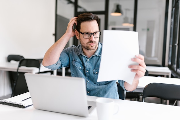 In verwarring gebrachte jonge mens die document bekijkt.