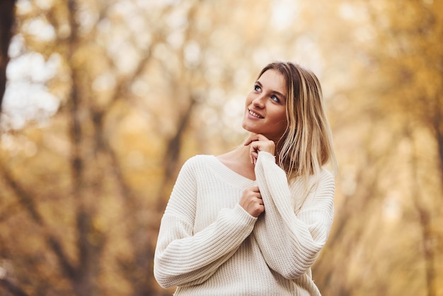 In warme kleding. Portret van een jonge brunette die overdag in het herfstbos is.