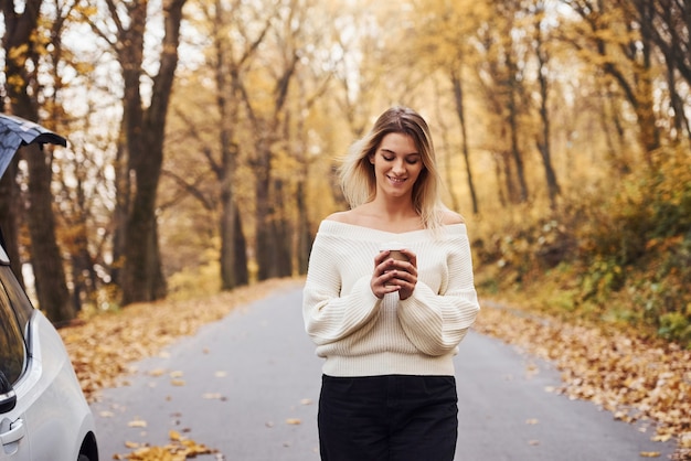 In warme kleding. Portret van een jonge brunette die overdag in het herfstbos is.