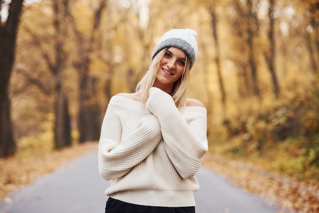 In warme kleding. portret van een jonge brunette die overdag in het herfstbos is.