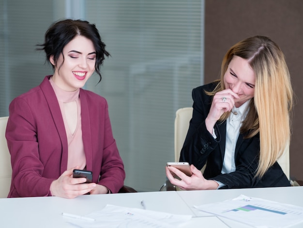 Inactieve werknemers kijken lachend naar hun mobiele telefoons.