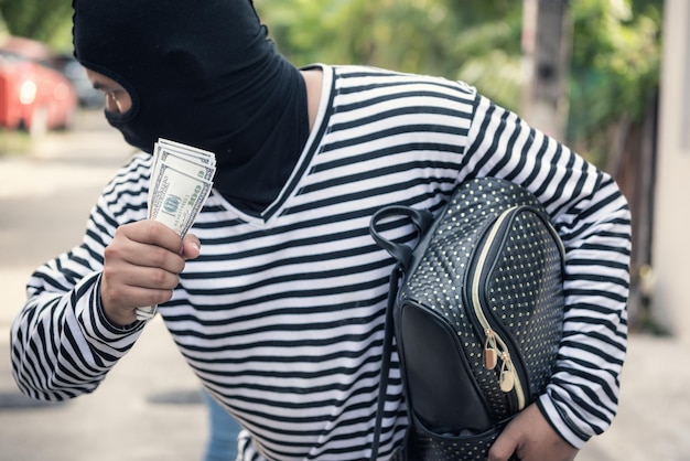 Foto inbreker met papiergeld en rugzak in de stad.