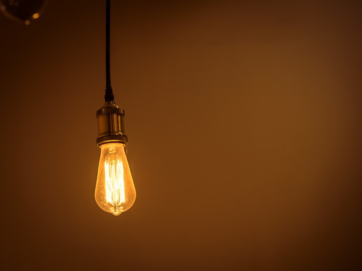 Photo incandescent light bulb is hanging decorated interior room. 