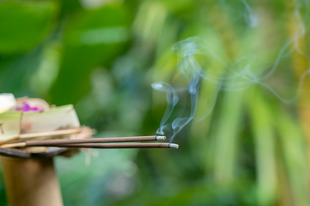 Incense stick burning with smoke for balinese hindu offering ceremony on central street in Ubud, Island Bali, Indonesia . Close up