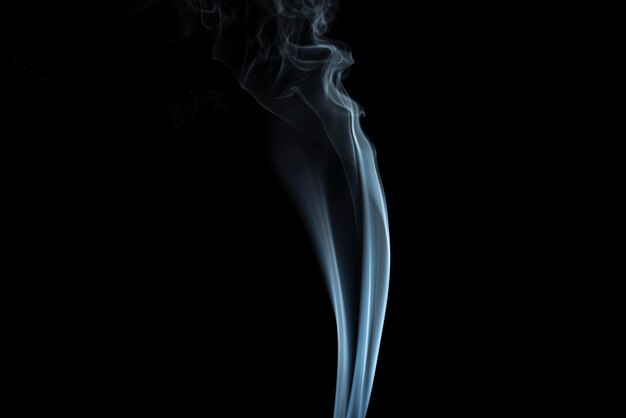 Incense stick with light blue smoke against black background