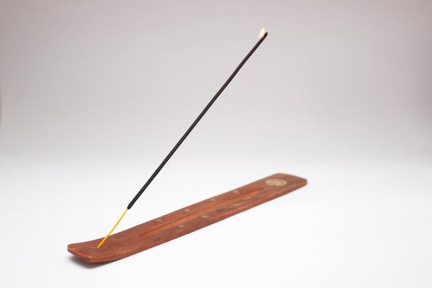 An incense stick on a wooden holder on a white background.