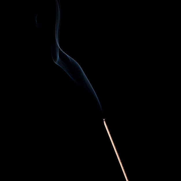 Incense sticks burning with smoke on black background