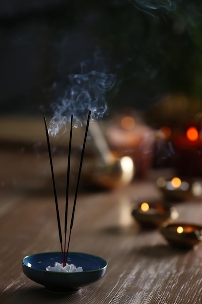 Incense sticks smoldering on wooden table in room