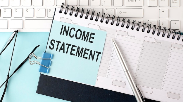 INCOME STATEMENT text on blue sticker on the planning and keyboardblue background