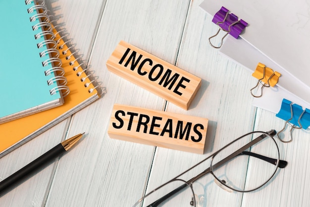 Income Streams words written on wooden blocks near office supplies