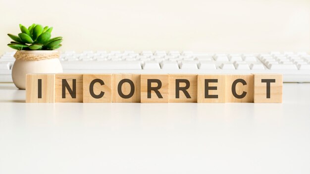 Incorrect word made with wooden blocks. front view concepts, green plant in a flower vase and white keyboard on background