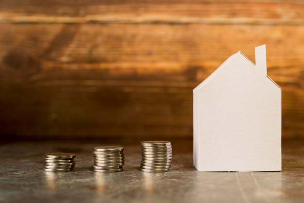 increasing stack coins near paper house surface