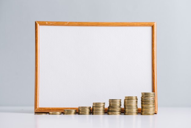 Photo increasing stacked coins in front of blank white board