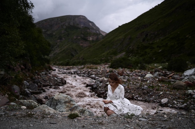 Incredible landscape of mountains and river Innocent pretty girl sits next to the river