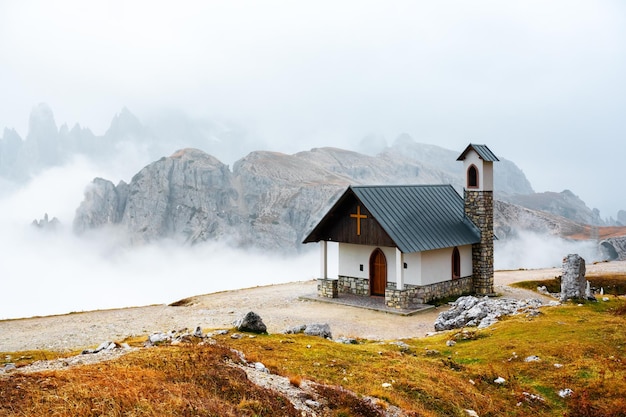 Incredible view on small chapel in the Tre Cime Di Laveredo National Park in morning fog Dolomite Alps mountains Trentino Alto Adige region Sudtirol Dolomites Italy