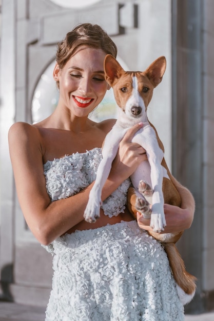 An incredibly beautiful woman in a gently turquoise taffeta with a pretty dog laughs