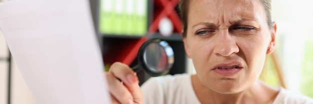 Incredulous middle age woman looking on document trough magnifying glass closeup concept of eye