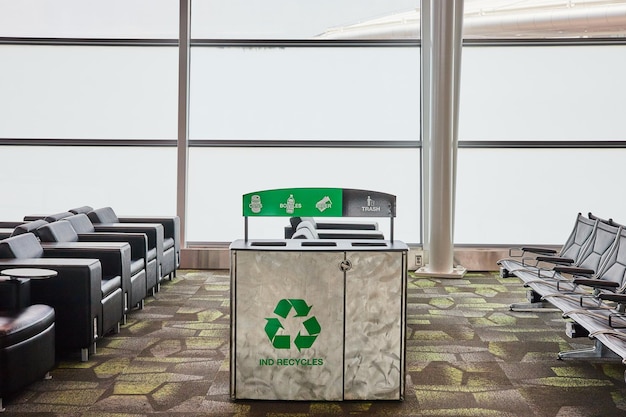 Photo ind recycles recycling receptacle in empty airport terminal with chairs and gray windows