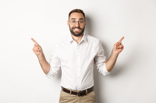 Indecisive businessman pointing sideways, showing two variants, struggling make choice, standing over white background