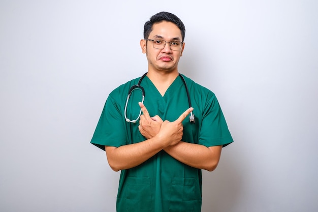 Indecisive and clueless asian male doctor dont know what choose\
pointing fingers sideways and shrugging unaware