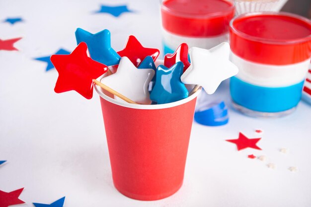 Photo independence day fourth of july usa american patriotic party with american symbols blue red white star shape hard caramel rock candy lollipops in paper cup