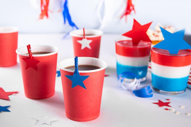 Independence Day Fourth of July USA American patriotic party with american symbols Paper cup with drinks and tasty dessert layered colorful jelly with stars on the background