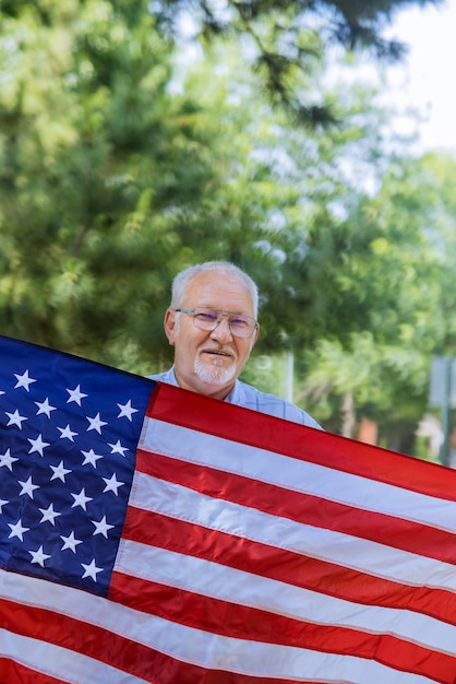 Independence day in happy senior patriot holds a stars and stripes a large American flag of U.S. federals holiday