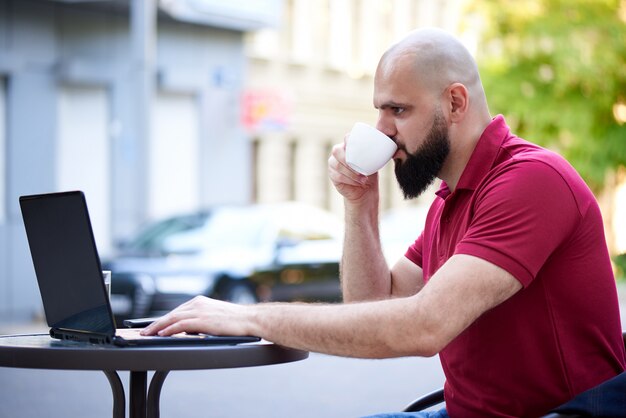 独立した若い男がカフェで働いています。