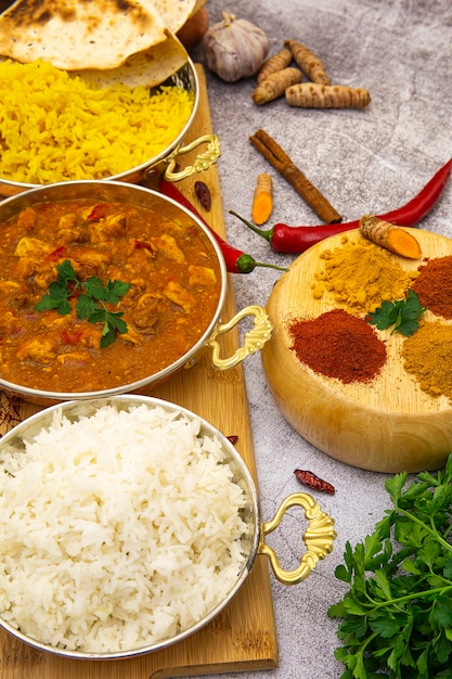 Foto indiaans eten. kerrie kip in tomatensaus met witte en gele rijst, kruiden: kerrie, kurkuma, hete en milde paprika