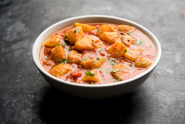 Indiaas eten - Aloo curry masala. Aardappel gekookt met specerijen en kruiden in een tomatencurry. geserveerd in een kom over humeurige achtergrond. selectieve focus