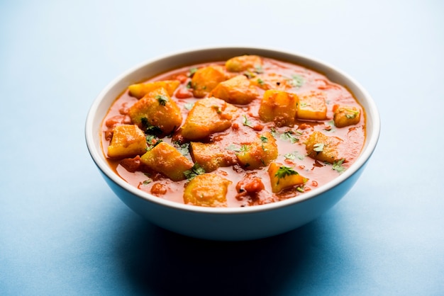 Indiaas eten - Aloo curry masala. Aardappel gekookt met specerijen en kruiden in een tomatencurry. geserveerd in een kom over humeurige achtergrond. selectieve focus