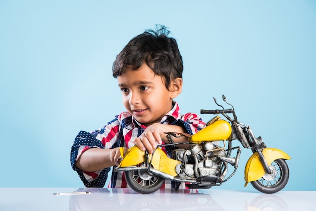 Indiaas klein kind dat een speelgoedmotor of minibike speelt of repareert