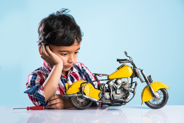 Indiaas klein kind dat een speelgoedmotor of minibike speelt of repareert