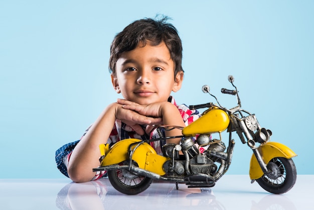 Indiaas klein kind dat een speelgoedmotor of minibike speelt of repareert